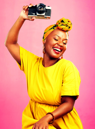 african american woman in a yellow dress holding an older model camera in her hand