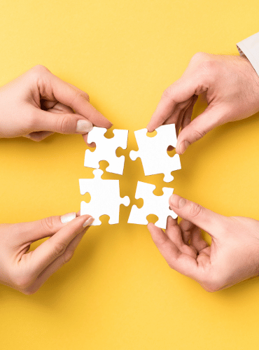 4 hands and 4 puzzle pieces symbolizing collaboration